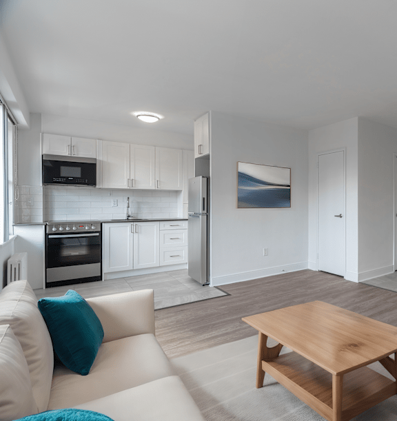 the living room and kitchen of an apartment with wood floors and white cabinets at 161 St. George, Toronto California