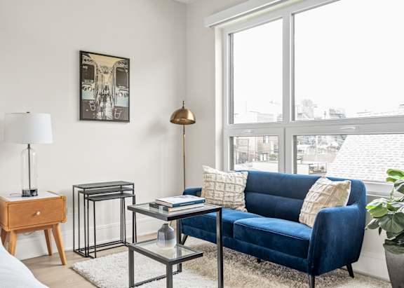 A blue couch sits in a living room with a table and lamp.
