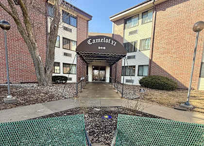 A green mesh fence is in front of a building with a sign that says "Camelot EZ".