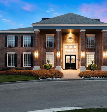 A large, well-lit house with a front yard and a driveway.