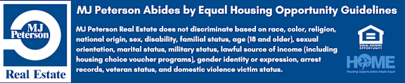 A blue and white sign that says MJ Peterson Real Estate does not discriminate based on race, color, religion, national origin, sex, disability, familial status, age, sexual orientation, marital status, military status