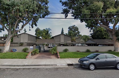A street view of a residential area with cars parked on the side of the road.