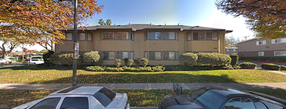 A beige two-story house with a white car parked in front.