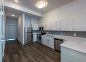 Thumbnail 4 of 7 - A kitchen with white cabinets and a wooden floor.