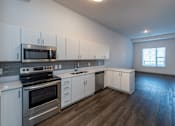 Thumbnail 3 of 7 - A kitchen with white cabinets and stainless steel appliances.