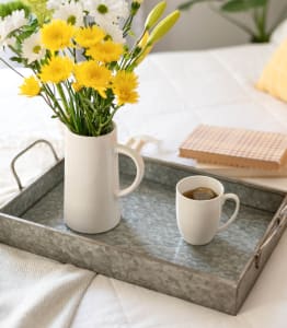 a tray with coffee and flowers on a bed