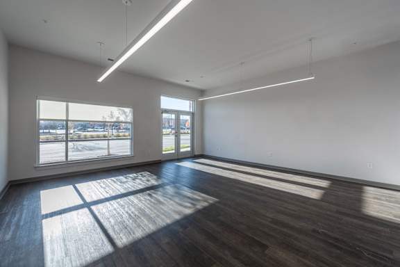 A large empty room with wooden floors and windows.