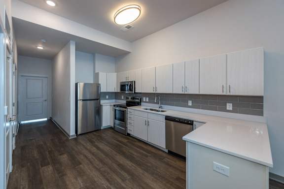 A kitchen with white cabinets and a wooden floor.