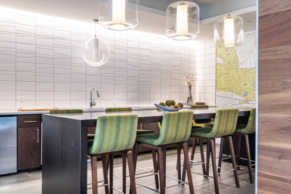 a kitchen with a long counter and green chairs