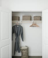 A grey robe is hanging on a hanger in a white closet at Villas of Mason Hills, Texas