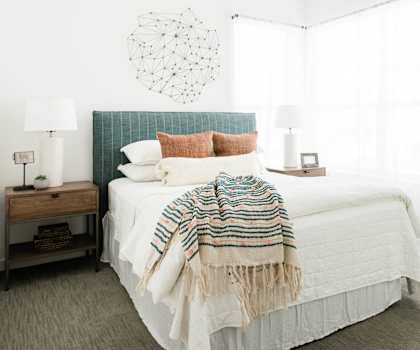 A bedroom with a bed covered in a white comforter and a green headboard at Villas of Mason Hills, Leander, Texas