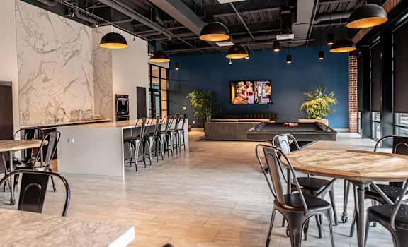 a dining area with tables and chairs and a pool table in the background at The Met at Metro Centre Apartments, Maryland