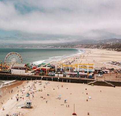 A crowded beach with a pier and amusement park.