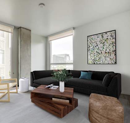 A modern living room with a black couch, wooden coffee table, and a large window.