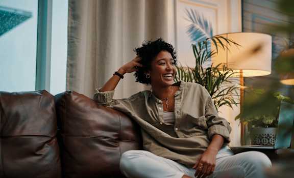 A woman is sitting on a brown leather couch.
