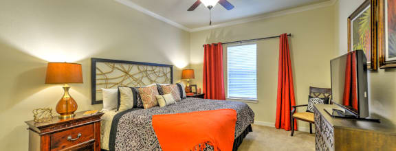 the master bedroom features a king sized bed and a flat screen tv at Hacienda Club Apartments in Jacksonville, FL