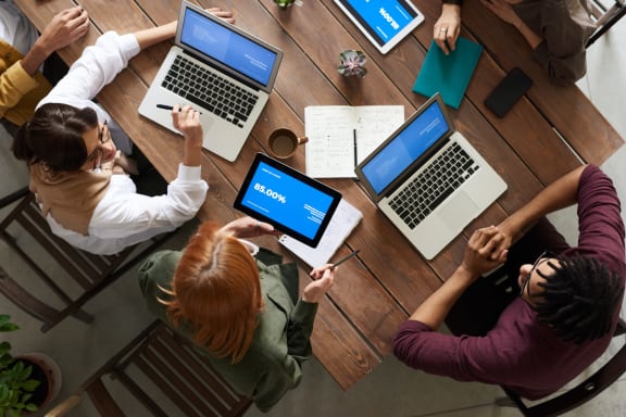 people sitting around a table with laptops