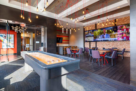 A billiard table is in the middle of a room with a brick wall and a TV.