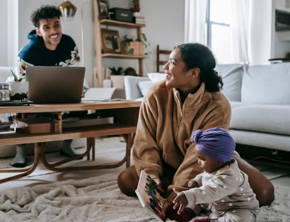 a family sitting on the floor in their living room looking at a laptop