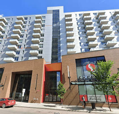 A modern building with a red car parked in front.