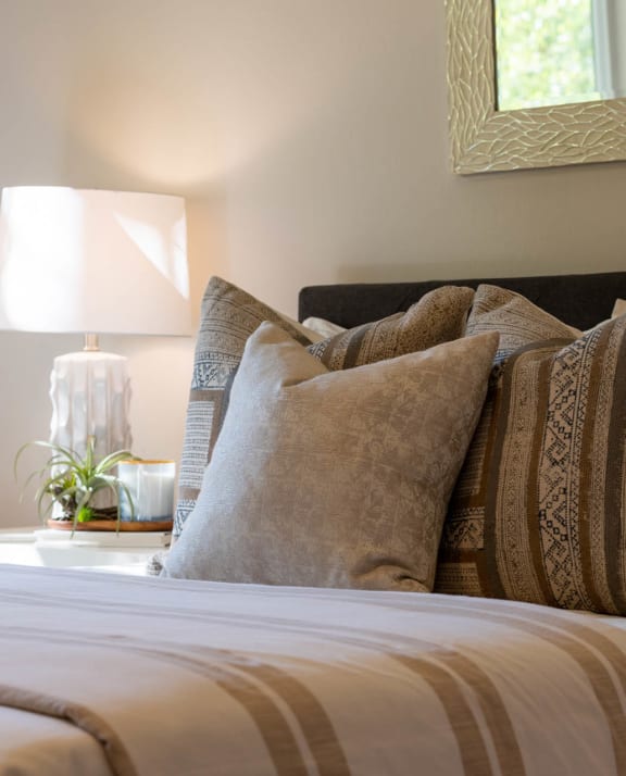 a bed with pillows and a table with a lamp