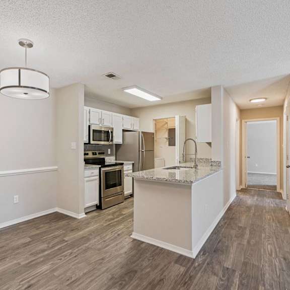 A kitchen with a white island and wooden floors.