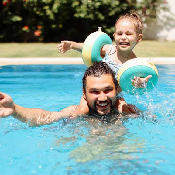 A man and a child are swimming in a pool.