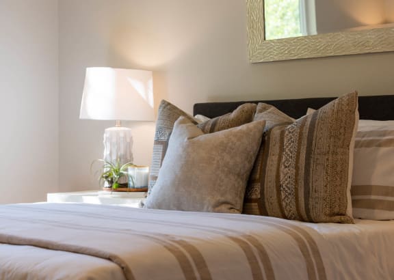 a bed with pillows and a table with a lamp