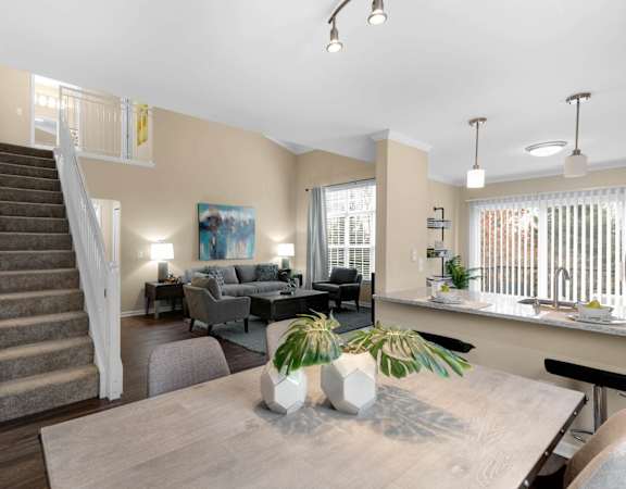 a living room with a wooden table and a staircase at Mainstreet Village, Novi, Michigan