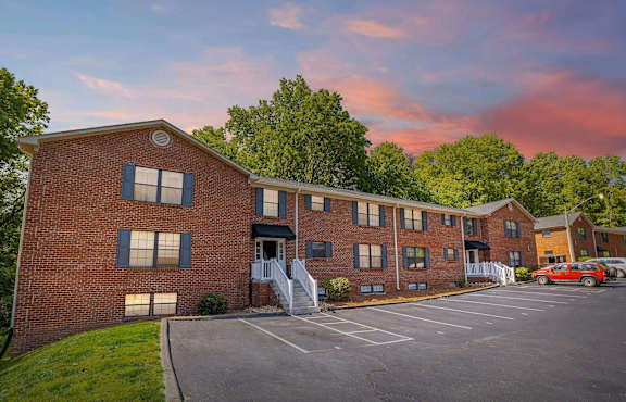 A red brick building with a parking lot in front.