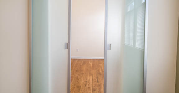 a sliding glass door leading into an empty room with a hardwood floor