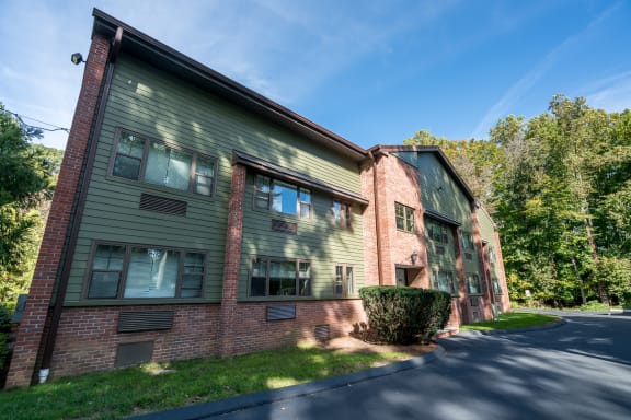 the exterior of a brick apartment building with green grass and trees
