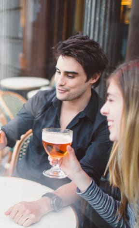 Three people are sitting at a table with drinks in a cafe.