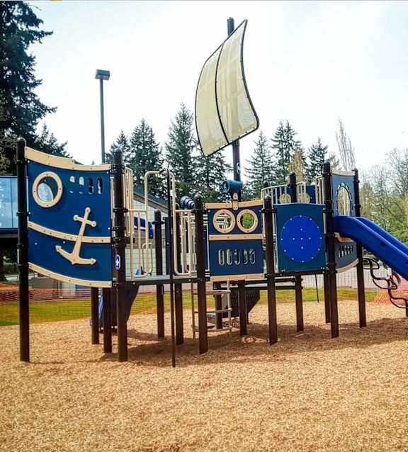 A playground with a blue slide and a white flag.