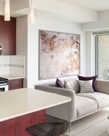 Open concept kitchen with an island, stools, and living room with  a couch and table.