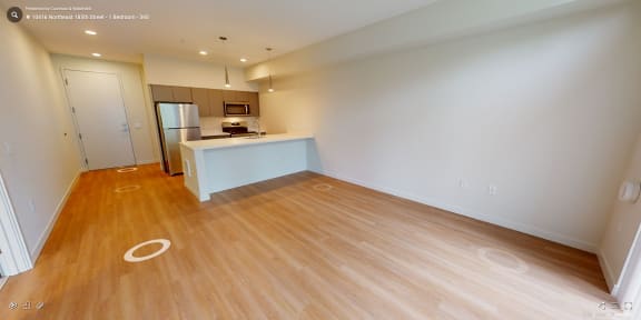 an empty living room and kitchen with wood flooring