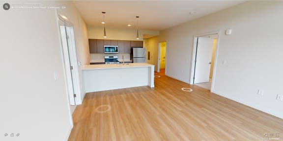 an empty living room and kitchen with wood flooring