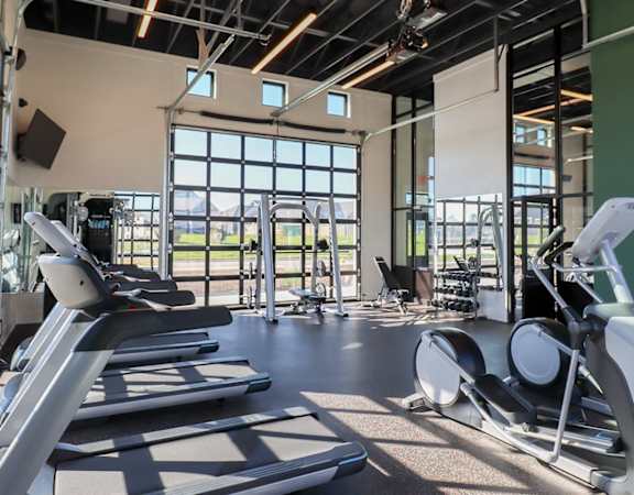a gym with cardio equipment and windows in a building
