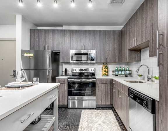 A modern kitchen with a stainless steel refrigerator, oven, and sink.