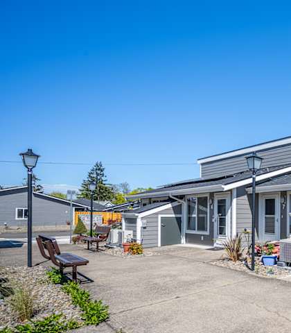 A grey building with a parking lot in front.