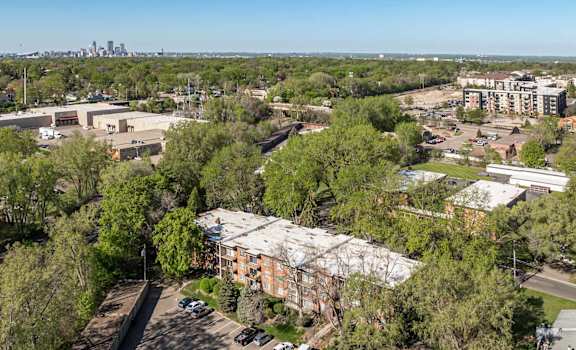 A parking lot is surrounded by trees and buildings.