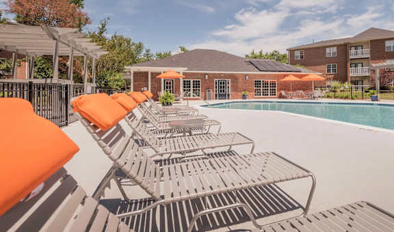 A pool surrounded by orange sun loungers and a building in the background.