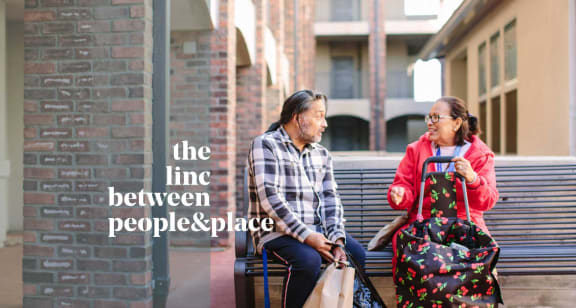 a man and a woman sitting on a bench with bags