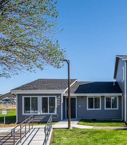 A grey house with a green lawn in front.