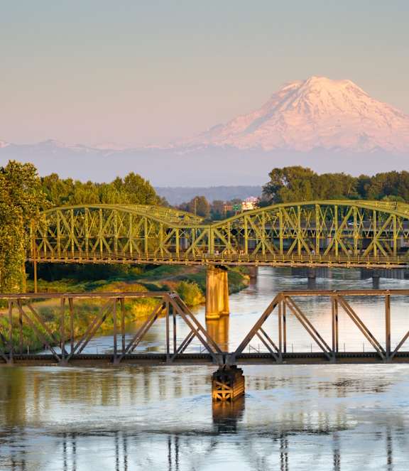 A bridge over a river with a mountain in the background.