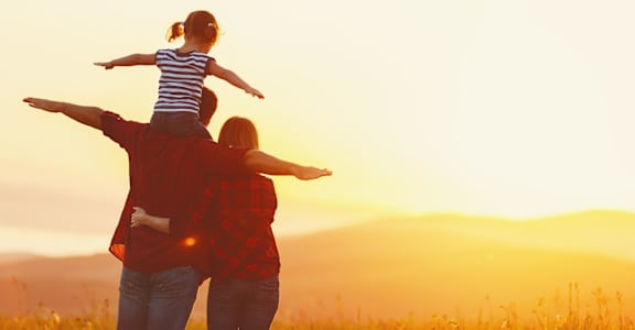 A woman and a child are enjoying a sunset in a field.