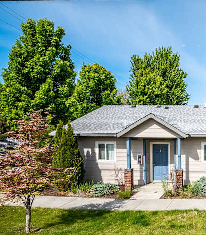 A house with a blue door and windows surrounded by greenery.