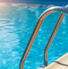 A pool ladder leading into a blue pool.