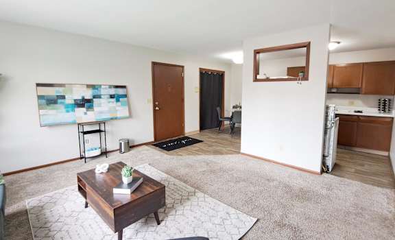 A living room with a brown coffee table and a blue and white abstract painting on the wall.