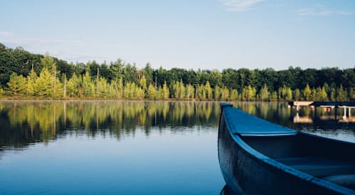 A boat sits on a calm lake with trees in the background.